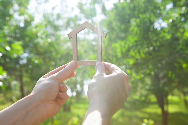 Holding a house in his hand on the background of nature