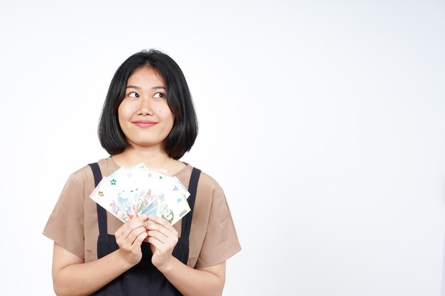 写真 白い背景に分離された美しいアジアの女性のインドネシアの新しい紙幣を保持しています。