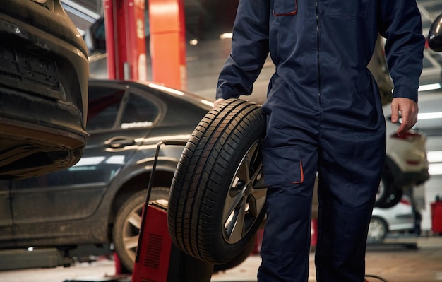 holding it in hand close up view of man that is moving tire of the car