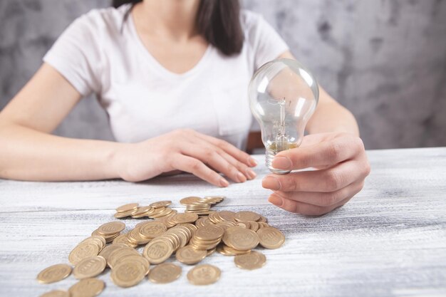 Holding a light bulb next to coins