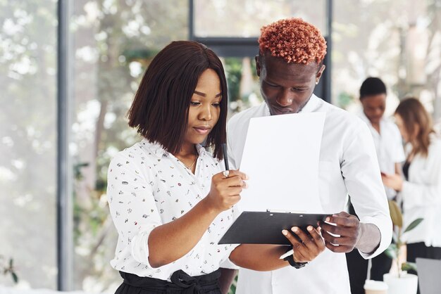 Holding notepad Group of african american business people working in office together