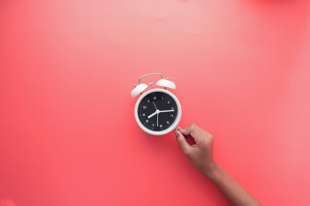 holding a old alarm clock on red background