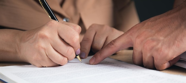 Holding a pen and pointing out where to sign the contract