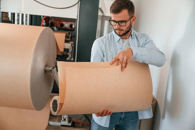 Foto tenendo pezzi di fogli di legno stampa lavoratore domestico in abiti bianchi è al chiuso