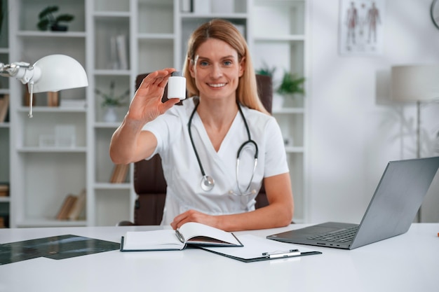 holding pills young female doctor in white coat is indoors