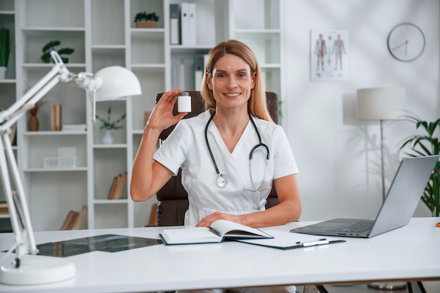 holding pills young female doctor in white coat is indoors
