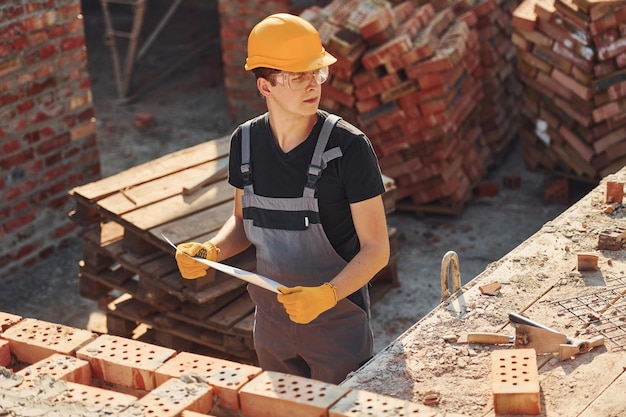 Photo holding plan in hands construction worker in uniform and safety equipment have job on building