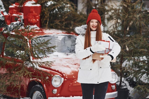 Photo holding present box happy young woman standing outdoors and celebrating christmas holidays