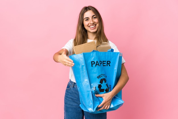 Holding a recycling bag full of paper to recycle over isolated pink handshaking after good deal