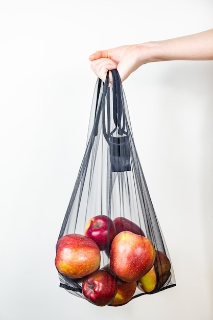 Holding a reusable string bag full of apples.