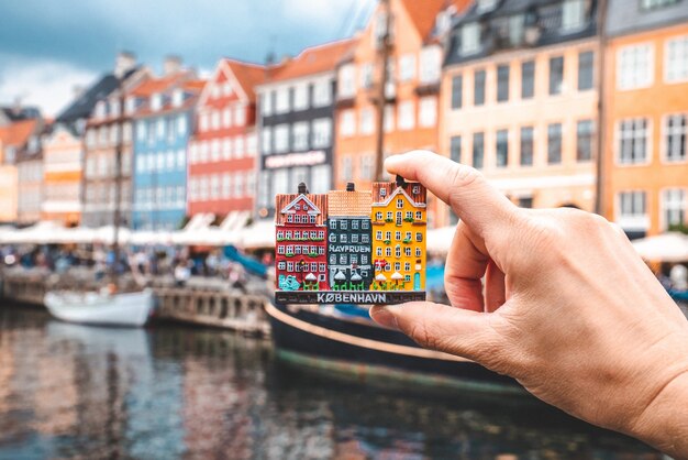 Holding a sculpture of famous Nyhavn colorful buildings with a real district in the background