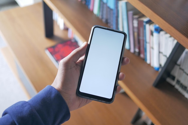 ライブラリの背景に対して白い画面でスマート フォンを保持