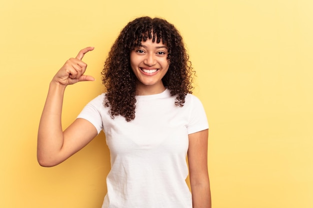 Holding something little with forefingers smiling and confident