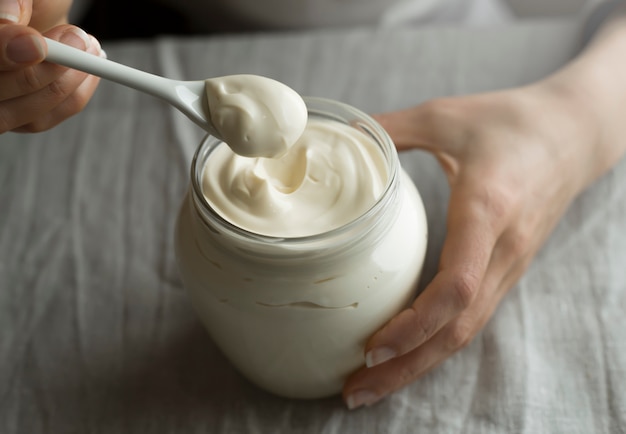 Holding sour cream in a glass jar with a spoon