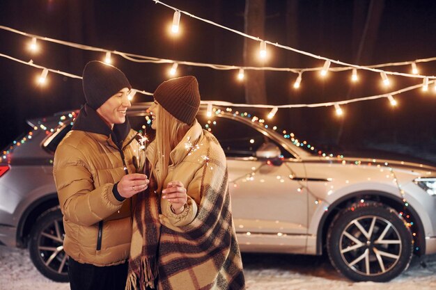 Holding sparklers Couple standing in the forest and celebrating New year