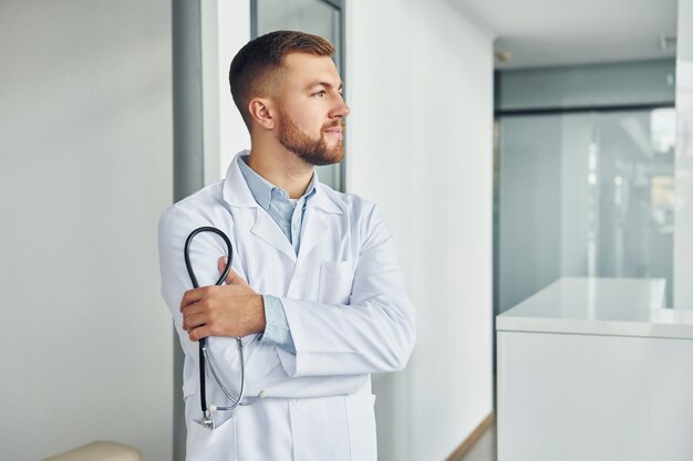 Tenendo lo stetoscopio il medico professionista in camice bianco è in clinica