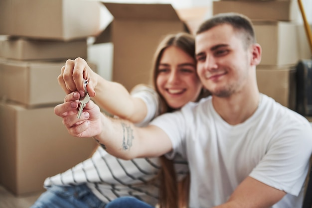 Holds keys of their new house. Successful people. Cheerful young couple in their new apartment. Conception of moving.