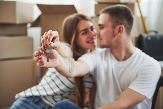 Holds keys of their new house. Successful people. Cheerful young couple in their new apartment. Conception of moving.