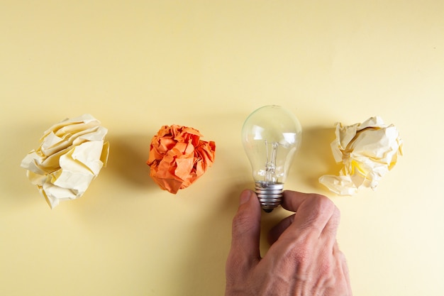 Foto tiene una lampadina accanto a pezzi di carta accartocciati