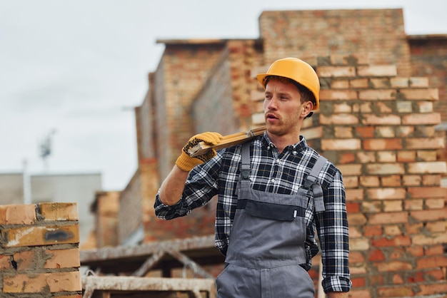 Photo holds measuring tool and takes break construction worker in uniform and safety equipment have job on building