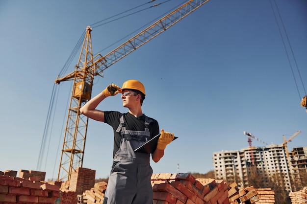 Holds notepad with documents Construction worker in uniform and safety equipment have job on building