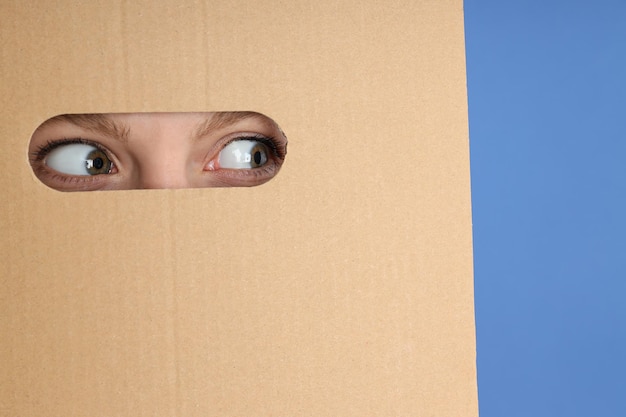 Photo hole in cardboard with young woman eyes