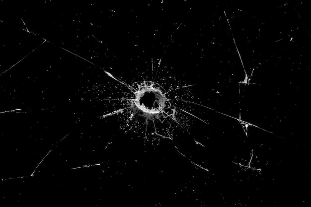 Hole in the glass with cracks isolated on a black background