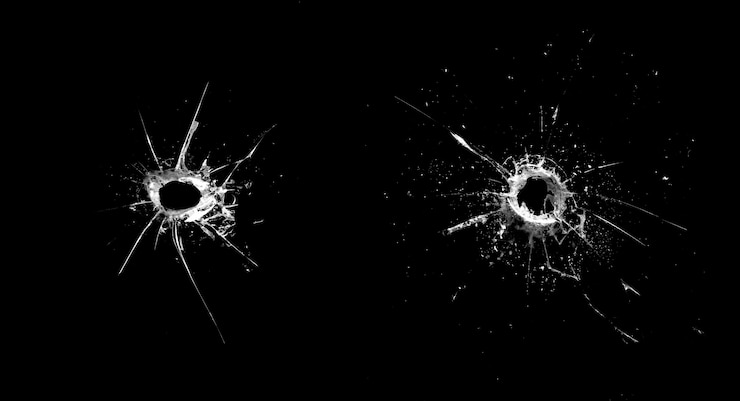 Photo hole in the glass with cracks isolated on a black background