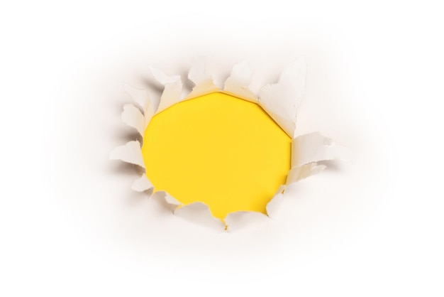 A hole in a white paper on a yellow background, copy space.