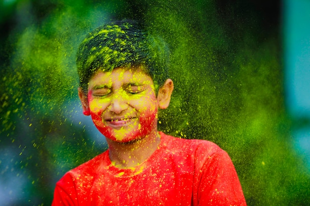 Празднование Холи - Индийский маленький мальчик играет на Холи и показывает выражение лица.