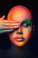 Foto festival dei colori di holi. ritratto di modello di bellezza con polvere colorata compongono in posa. bella donna con il trucco arcobaleno. trucco artistico colorato astratto, raccolto