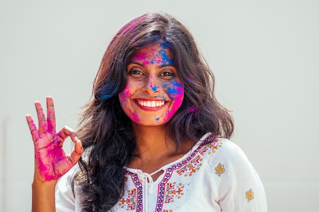 Holi Festival Of Colors Portret van een gelukkig Indisch meisje in holi-kleuren die een goed gebaar toont, oké?