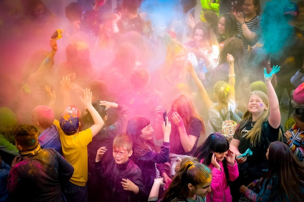 Holi indiase feestdag jonge mensen in de menigte gooien gekleurde poeders omhoog en hebben plezier gezichten