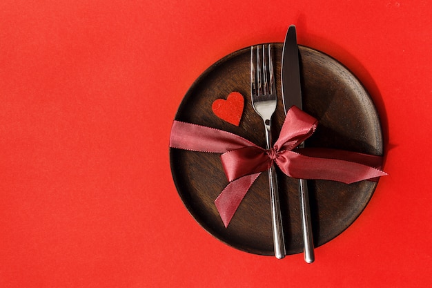 Holiday arrangement of plate with silverware on red background. 