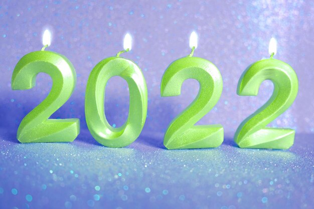 休日の背景明けましておめでとうございます2022年。ボケのお祝いのきらめく背景に金のキャンドルで作られた2022年の数。年末年始を祝う、クローズアップ。燃える数字。