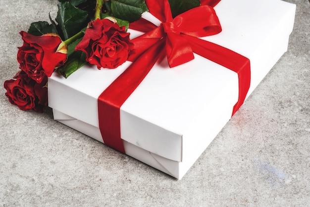 Sfondo vacanza, san valentino. bouquet di rose rosse, cravatta con un nastro rosso, con confezione regalo incartata