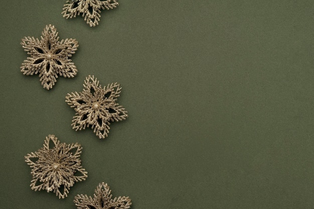Holiday border made gold shiny christmas snowflakes on green background Happy Christmas Xmas and New Year concept Top view Flat lay Copy space