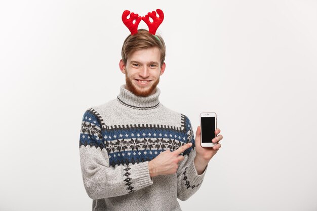 Holiday and Business Concept Young handsome man showing mobile phone display and pointing finger presenting