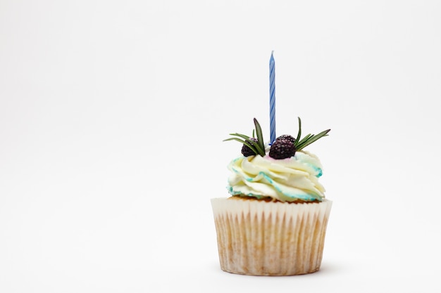 Holiday, celebration, greeting and party concept - birthday cupcake with one burning candles over white surface