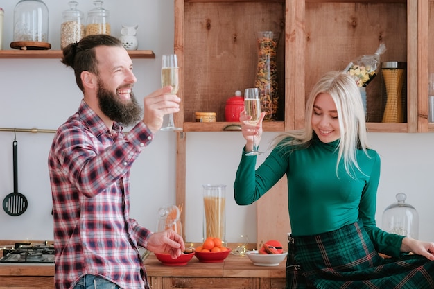 Holiday celebration. Happy couple having fun, drinking champagne in modern kitchen.