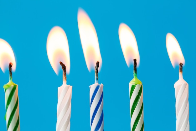 holiday, celebration and party concept - birthday candles burning over blue background and extinguished