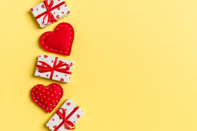 Holiday composition of gift boxes and red textile hearts on table with empty space