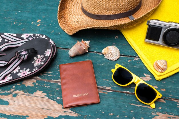 Holiday Concept Vintage wood table with holiday accessories Straw hat sunglasses flip flops shells vintage camera towel and passport