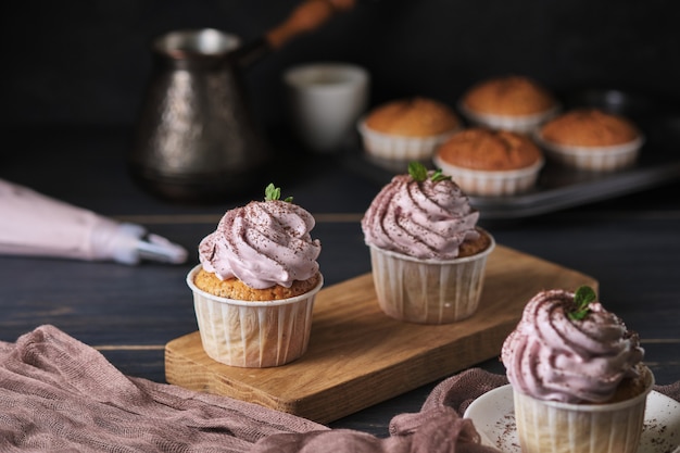 ピンクのクリームと休日のカップケーキ。デザートはミントの葉とチョコレートチップで飾られています。