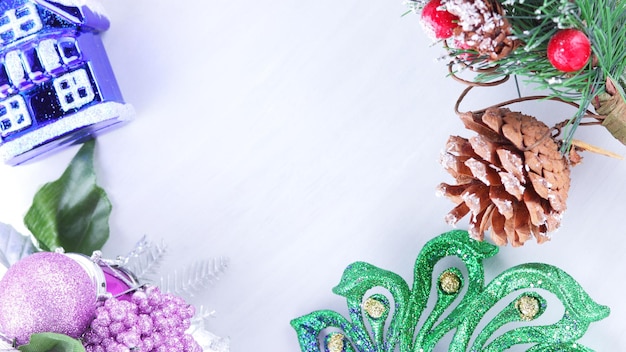 Holiday decorations on fir branch. Christmas decorations on white background. Pine cone and red berries on fir branch. Purple ball and colorful toy houses