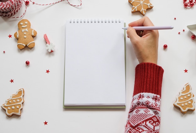 Holiday decorations and notebook with clean note book on white table, flat lay style.