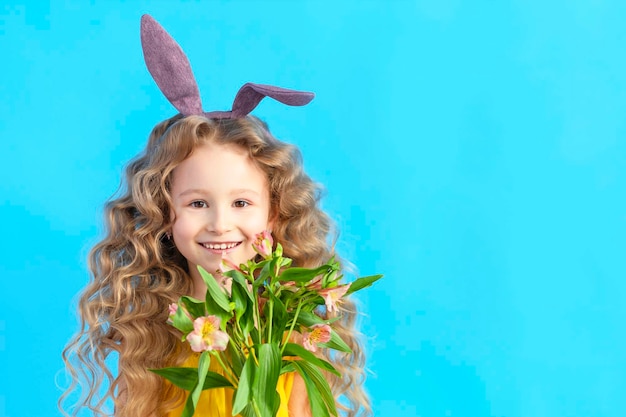 Photo holiday easter kids smiling girl with rabbit hare bunny ears spring flowers on blue