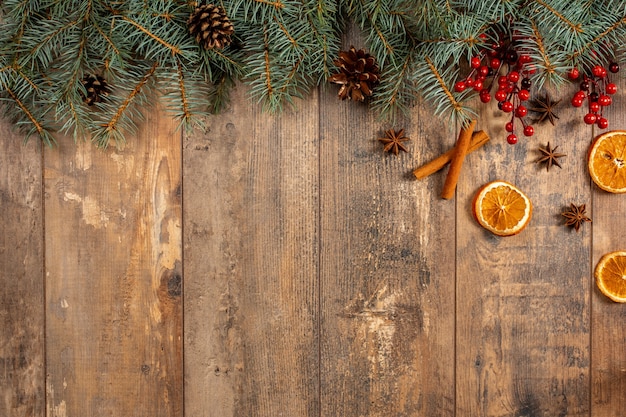 Holiday Evergreen Branches and Berries Over Rustic Wood Background.