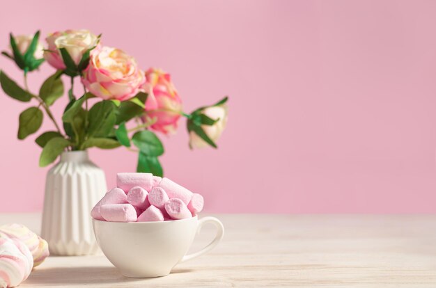 Holiday festive romantic table decorated with flowers and a cup with poink marshmallows