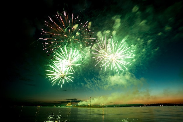 Holiday fireworks above water with reflection on the black sky background